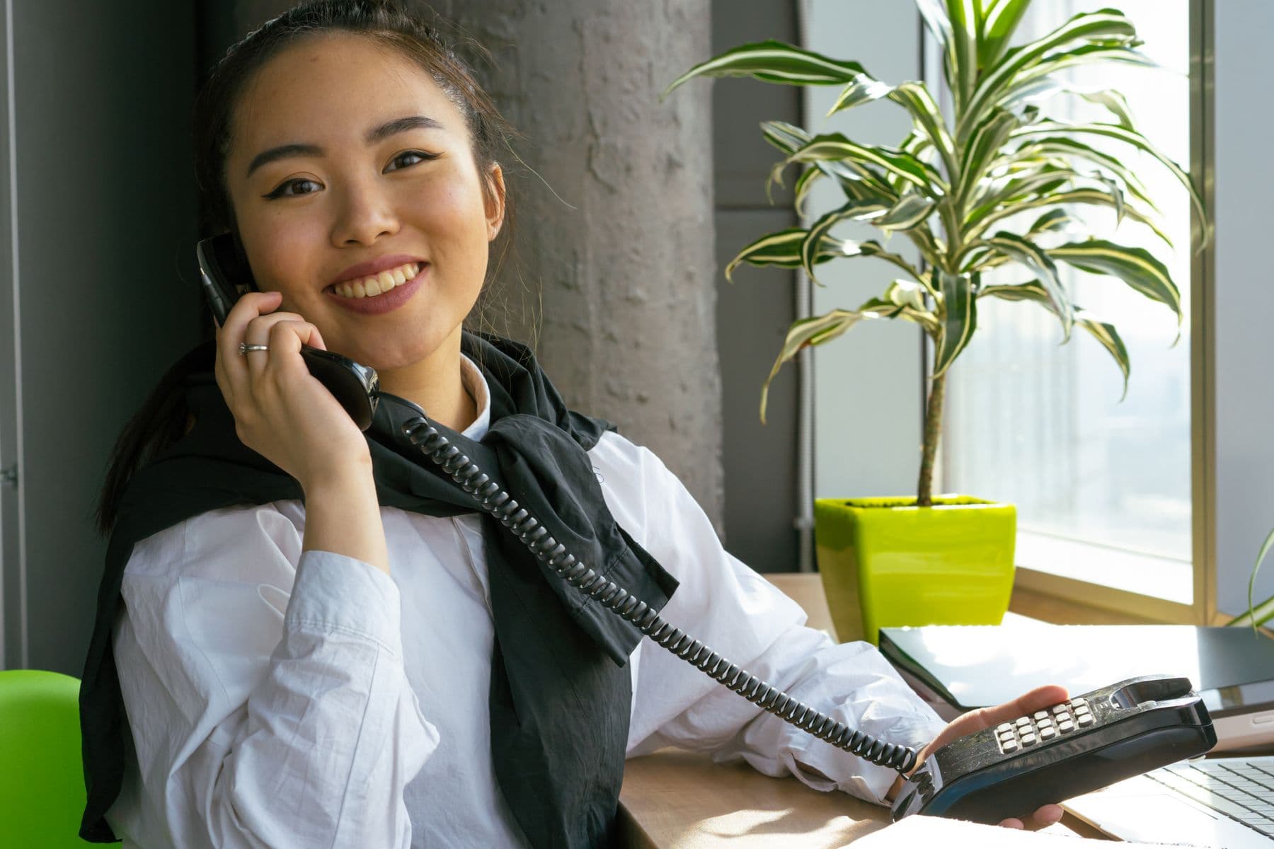 A friendly coordinator answering a phone call in a bright office
