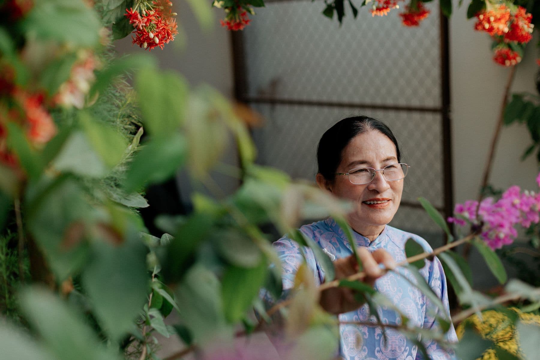 An older woman enjoying flowers in a home garden