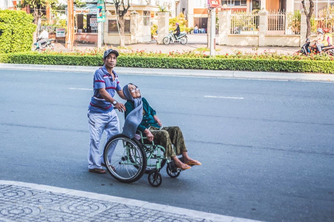A support person assisting an older woman in a wheelchair outdoors