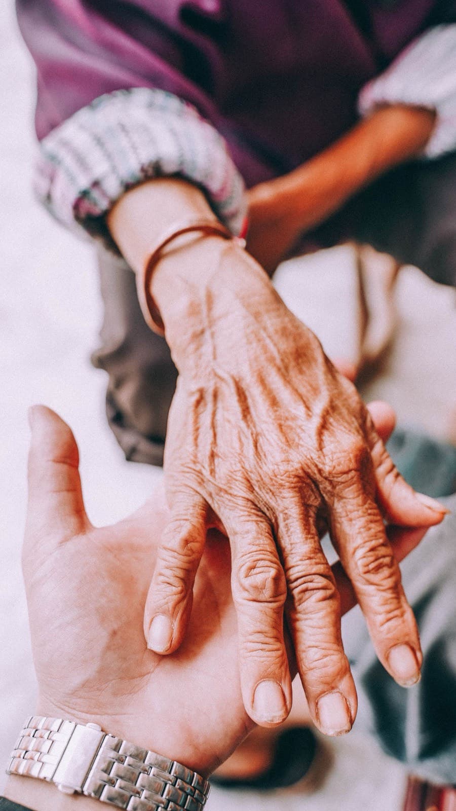 A supportive hand holding an older person’s hand